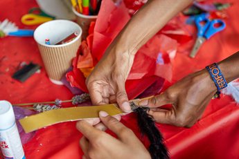 Close up of hands doing a craft activity and sticking a feather to a piece of paper.