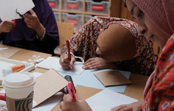 A group of adults writing and drawing while sitting at a table.