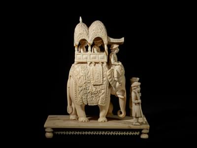 Side view of a statue with elephant carrying people.