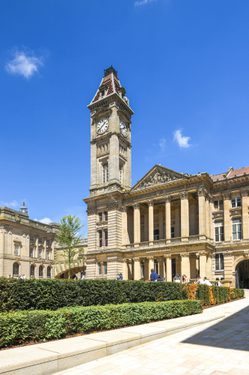 Photo ofshowing the front of Birmingham Museum and Art Gallery. The tall clock tower of the building is surrounded by blue sky.