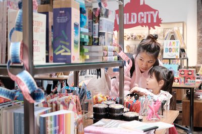 A woman and child explore colourful stationery and books in a shop.