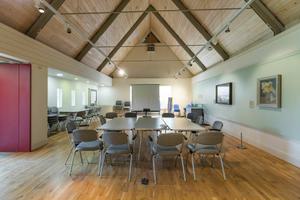 A room with vaulted ceiling and table and chairs in the middle.