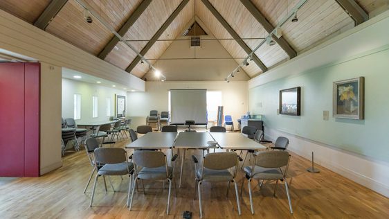 A room with vaulted ceiling and table and chairs in the middle.