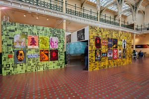 Bright posters that advertised the Que club are on display. There is a slight view in to a large box like space that constructed to show a film.