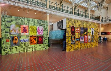 Bright posters that advertised the Que club are on display. There is a slight view in to a large box like space that constructed to show a film.