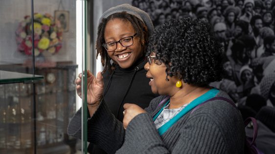 Two smiling people looking into a display case.