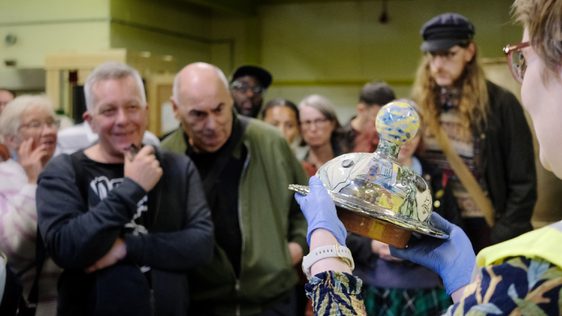 A staff member holding an object in front of a group of people.