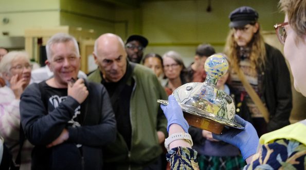 A staff member holding an object in front of a group of people.