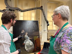 Two staff members looking at a painting in a conservation studio.