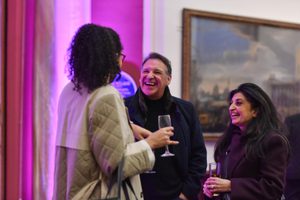 Three people in a gallery smiling and talking in an art gallery.