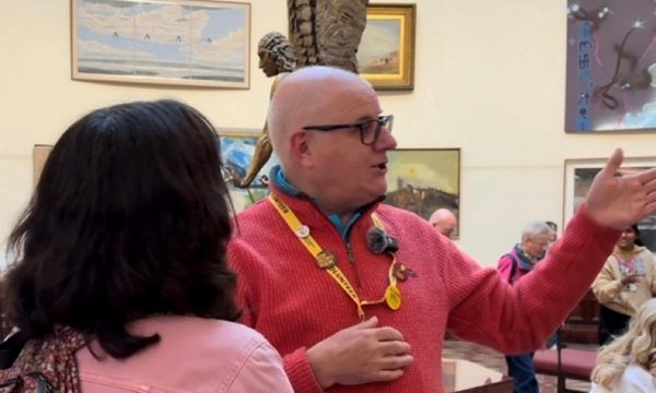 A volunteer talking to a visitor in a gallery setting.