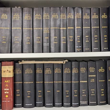 Two rows of books in a cupboard entitled City of Birmingham Museum and Art Gallery'.