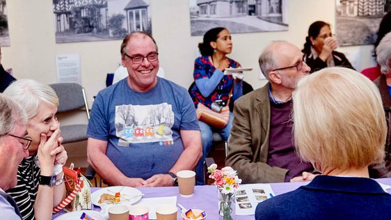 A group of people smiling while sitting and having lunch.