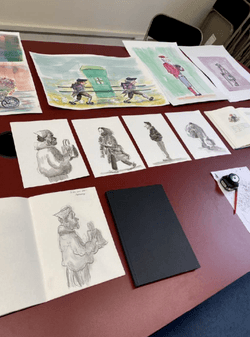A selection of drawings and paintings on a table.