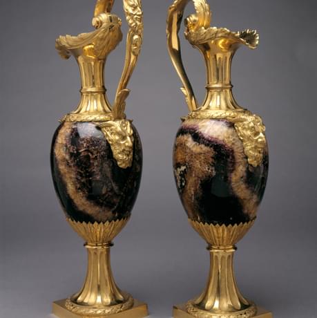 Two ornate jugs with gold coloured spouts, handles and bases, the middle parts are made of a polished blue stone