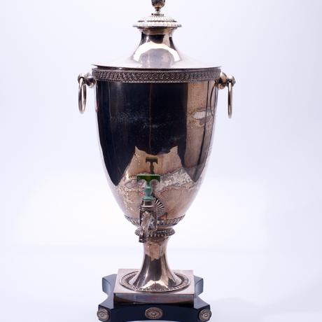 Silver container for liquid tea, shaped like an urn with a tap on the front