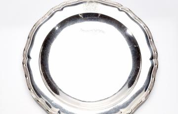 A round silver plate with decorated edge