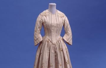 Long, striped 19th century dress with long sleeves, a full skirt and fitted waist