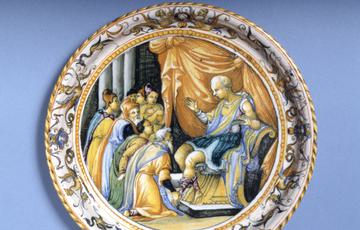 Round ceramic plate, patterned around the edge, with a painted scene in the middle from Ancient Roman history