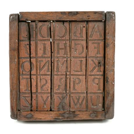 Wooden box frame containing reversed letters of the alphabet