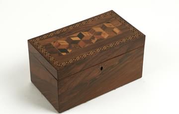 Small oblong wooden box with cube pattern on lid, designed to hold loose tea