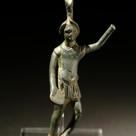 Metal figure holding left arm aloft, the hand is missing