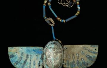 Blue pottery charm in the shape of a beetle with wings, a beaded pottery chain is attached to the top