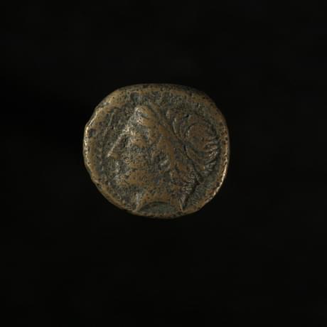 Dark coin, worn smooth, with the head of a figure looking to the left inscribed
