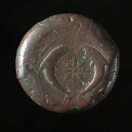 Dark coin, worn smooth featuring two fish circling each other
