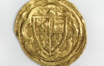 Misshapen gold coloured coin featuring a coat of arms