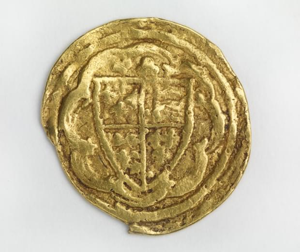Misshapen gold coloured coin featuring a coat of arms