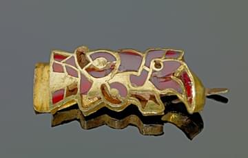 Small ornate gold artefact, inlaid with pieces of garnet stones, in the shape of a bird