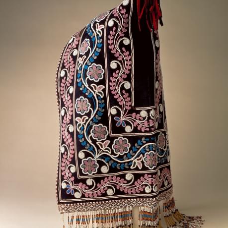 Cloth hood embroidered with a pattern of flowers with a beaded fringe on the bottom and tassel on the top
