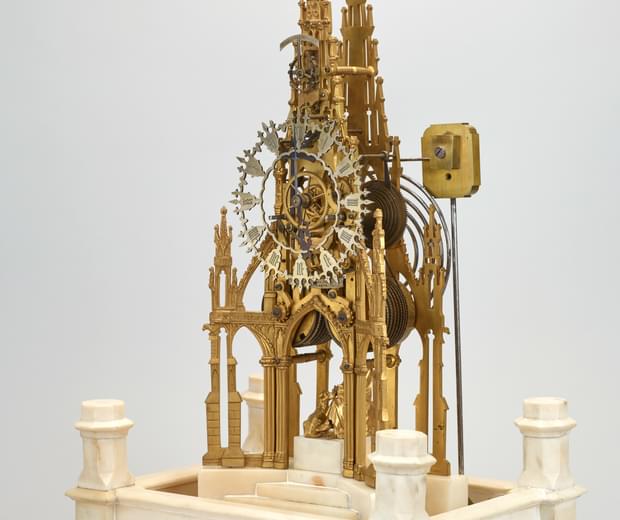 A clock made of delicate gold pieces, in the shape of the framework of a grand building. The cogs, face and handles of the clock are completely exposed