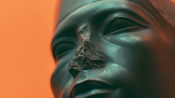 Close of a sculpture - figures face with bright orange background