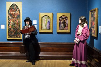 Two people dressed in period costume standing in an art gallery.