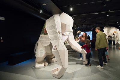 An exhibition space with 3D giant ape with children in front with text and graphics on the side.