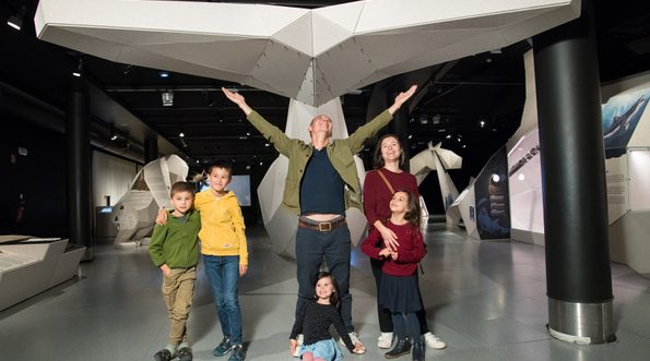 An exhibition space with 3D whale tail with a family in front.