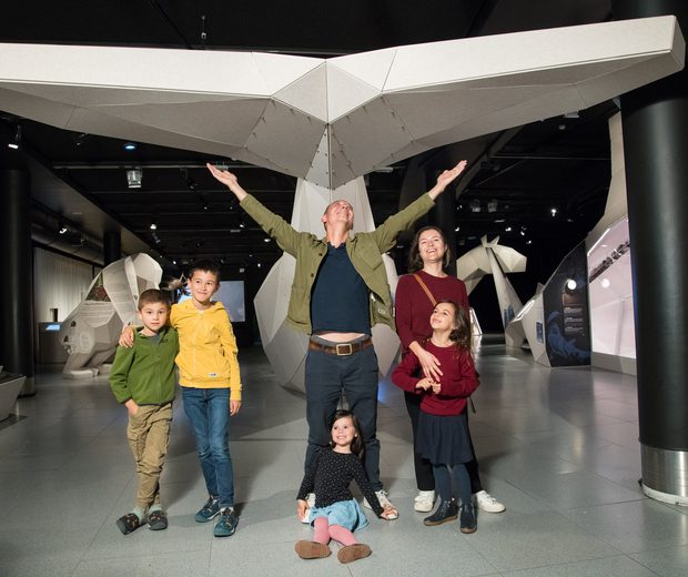 An exhibition space with 3D whale tail with a family in front.
