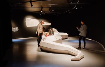 A family in an exhibition space with giant 3D prehsitoric snake
