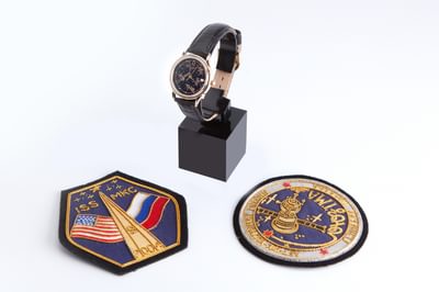 A collection of three objects including a watch and two ISS badges.