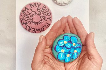 Hands holding a blue flowery clay artwork, with two other artworks on the table.