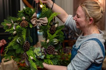 A smiling person holding up a wreath.