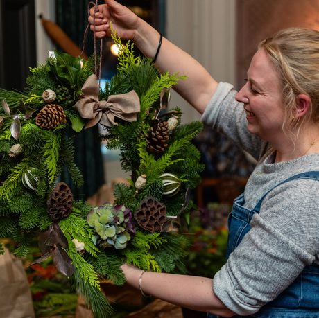 A smiling person holding up a wreath.