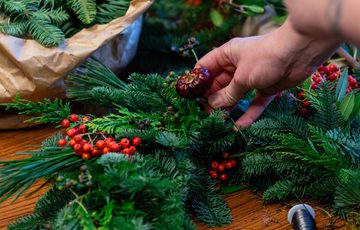 Close up of hands adding items to a wreath.