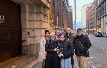A group of people standing on a pavement holding a film clapper