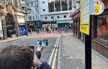 A picture of a man holding a photograph in a street scene