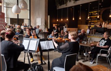 A group of musicians perform in front of a crowd in a coffee shop.