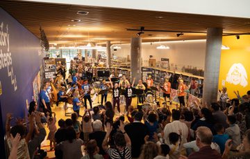 A large crowd watch a group of musicians perform in an indoor venue.