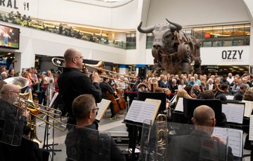 Music performers play in front of a large crowd in New Street train station.
